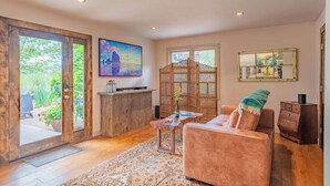 A spacious living area with a sofa, coffee table, and a TV mounted on the wall. - Refugio Cosetta (Paso Robles)
