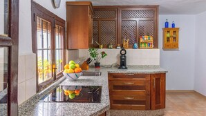 A kitchen with a granite countertop, wooden cabinets, a sink, and a fruit bowl. - La Zaranda de Pinillos Antequera by Ruralidays (Málaga)
