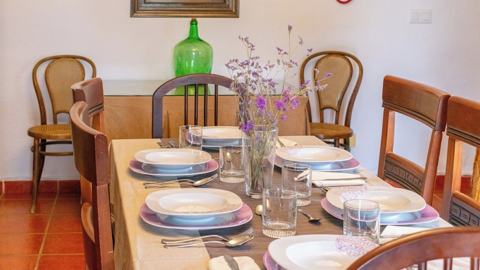 Une table à manger dressée avec des assiettes, des verres et des couverts.