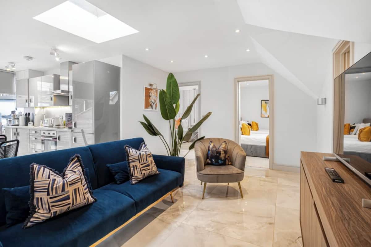 A modern living room with a blue sofa, a wooden TV stand, and a large plant.