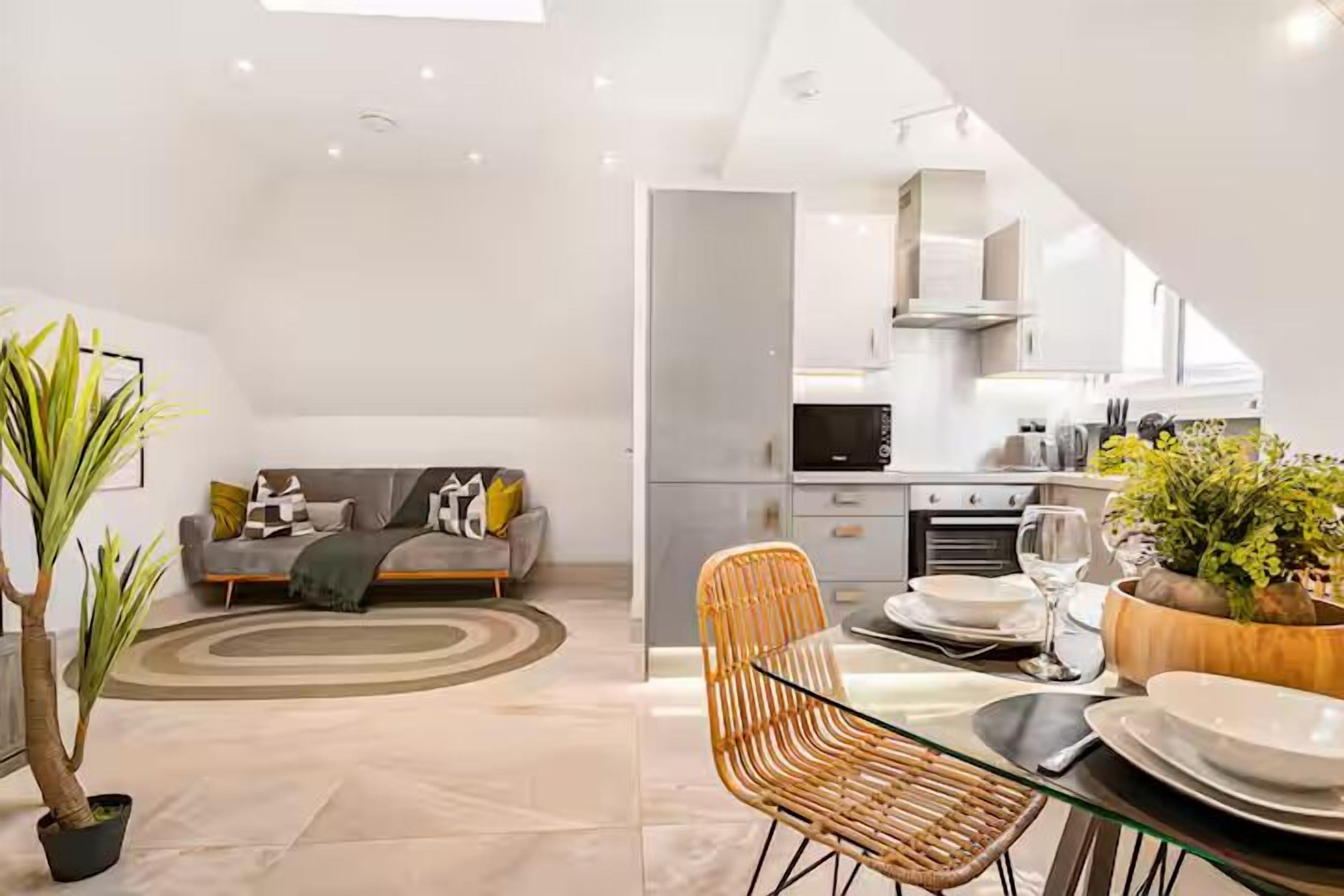 Ein modernes Wohnzimmer mit einer Couch, einem Esstisch mit Stühlen und einer Küche im Hintergrund.