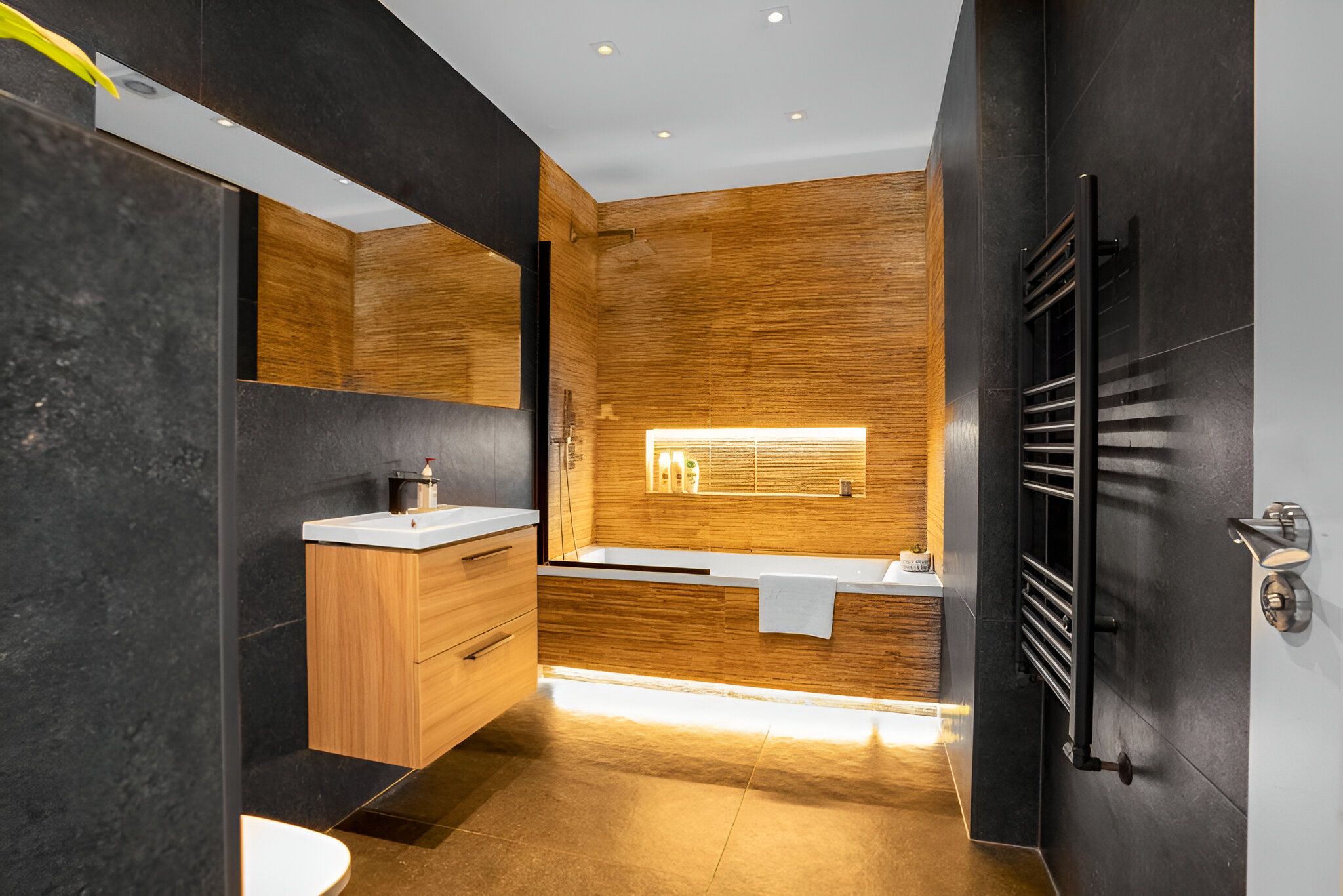 Une salle de bain moderne avec un meuble-lavabo en bois, un grand miroir et une fenêtre intégrée.