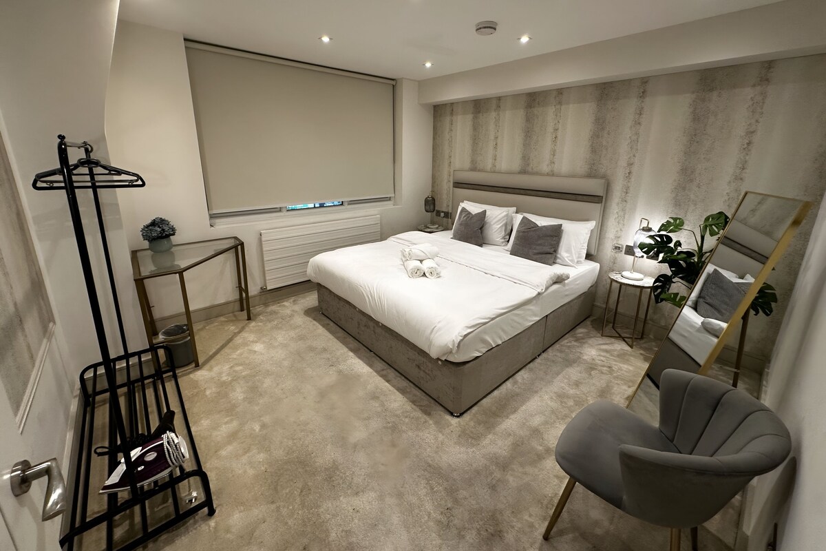 Une chambre moderne avec un grand lit, des tables de chevet, une chaise et un miroir.
