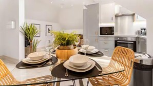 Un comedor moderno con mesa de vidrio, sillas de mimbre y una planta en maceta.