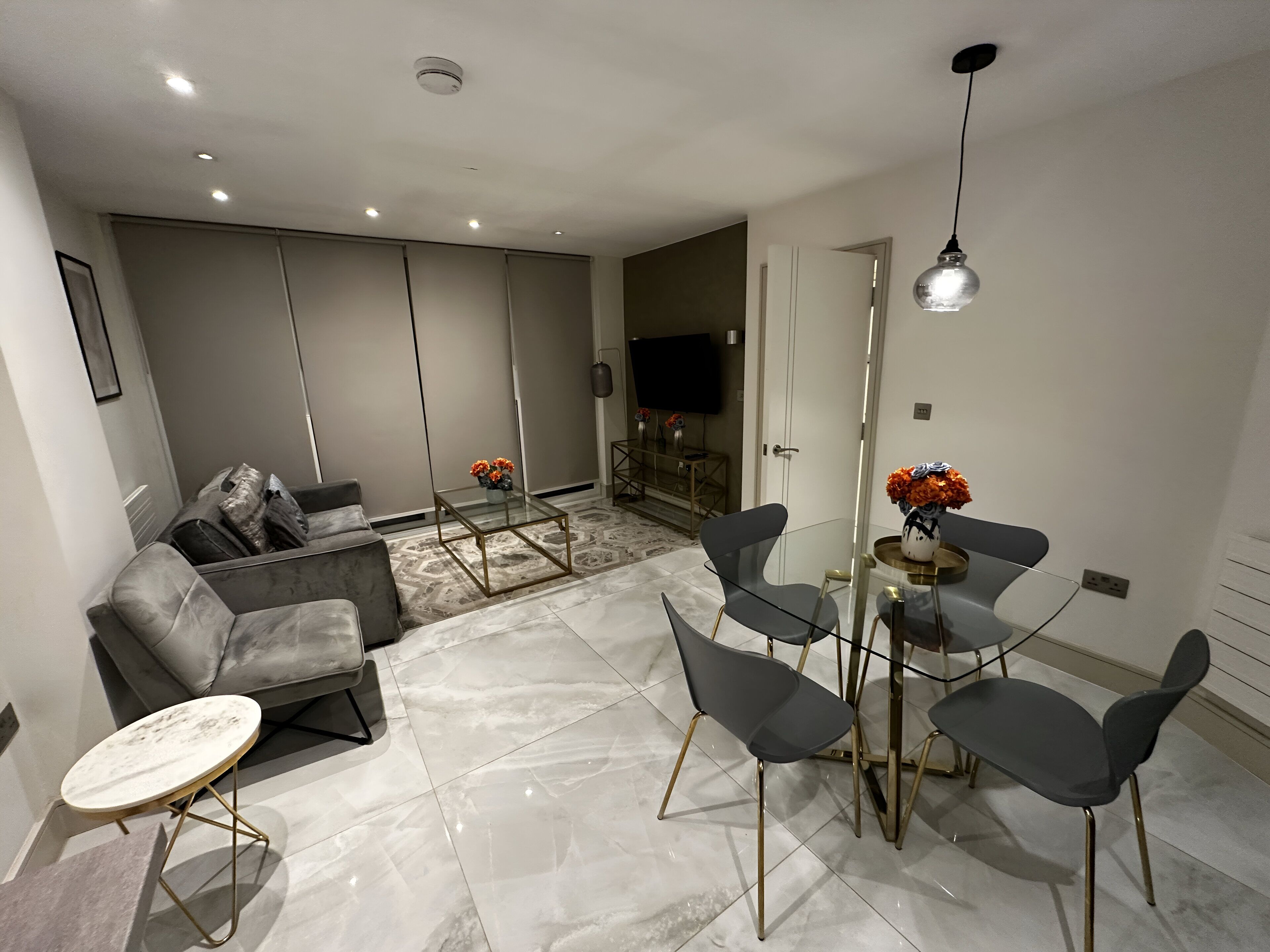 A modern living room with a sofa, a glass coffee table, and a dining area with chairs and a table.