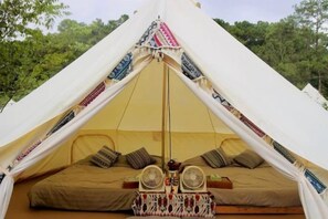 Una carpa con cama, almohadas y un ventilador.