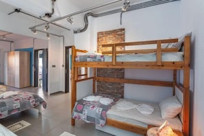 A bunk bed room with a stone accent wall, a wooden wardrobe, and a bathroom visible in the background.