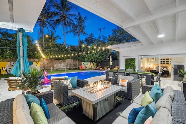 An outdoor patio with a pool, seating area, and a fire pit.
