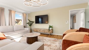 Ein modernes Wohnzimmer mit einer Couch, einem Couchtisch und einem an der Wand montierten Fernseher.
