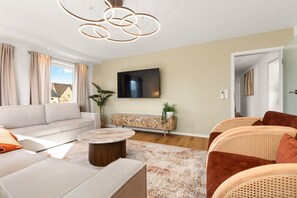 A modern living room with a sofa, a coffee table, and a TV mounted on the wall. - Luxury suite with whirlpool in the center (Bad Aibling)