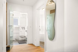 A modern bathroom with a glass shower enclosure, a toilet, and a mirror. - Luxury suite with whirlpool in the center (Bad Aibling)