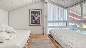 A bedroom with two beds, a wooden floor, a large window with blinds, and a poster on the wall. - Nice home in Aabenraa with swimming pool (Aabenraa)