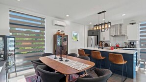 Cozinha moderna com ilha central, banquetas e área de jantar com mesa comprida e cadeiras.