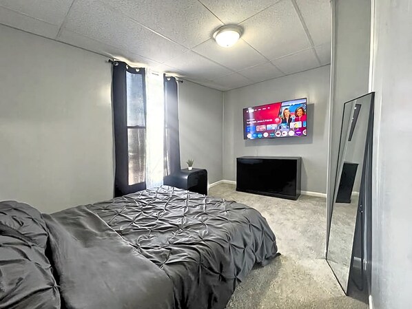 Ein Schlafzimmer mit einem Bett, einem an der Wand befestigten Fernseher und einem Kamin.