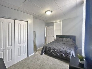 Une chambre à coucher avec un lit, une table de chevet, une plante en pot et une armoire.