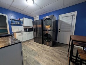Eine kompakte Küche mit integrierter Waschmaschine und Trockner, weißen Schränken und einer Holz Arbeitsplatte.