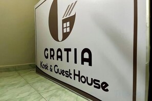 A sign for 'GRATIA Kost & Guest House' with a logo and text. - Gratia Guesthouse Syari'ah (Mendalo Darat)