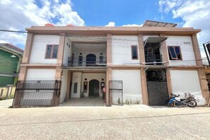A two-story residential building with a balcony, a gated entrance, and a motorcycle parked outside.