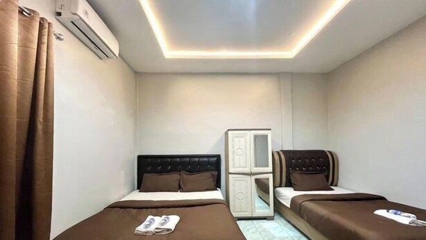 A hotel room with two beds, a wardrobe, and an air conditioning unit.