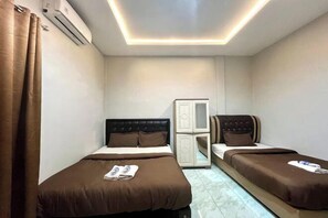 A hotel room with two beds, a wardrobe, and an air conditioning unit. - Gratia Guesthouse Syari'ah (Mendalo Darat)