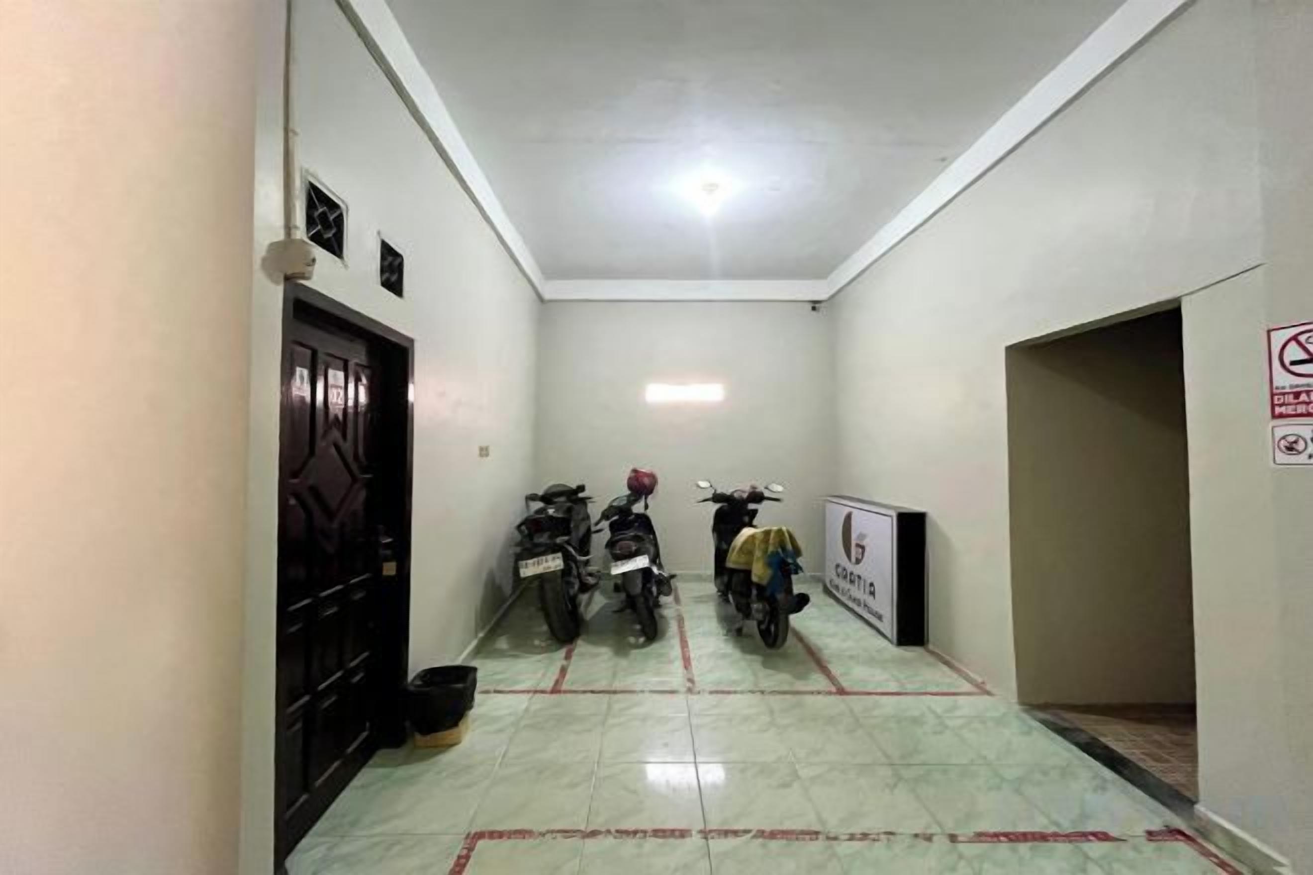 A narrow hallway with two motorcycles parked, a door on the left, and a sign on the right wall.