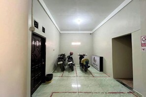 A narrow hallway with two motorcycles parked, a door on the left, and a sign on the right wall.