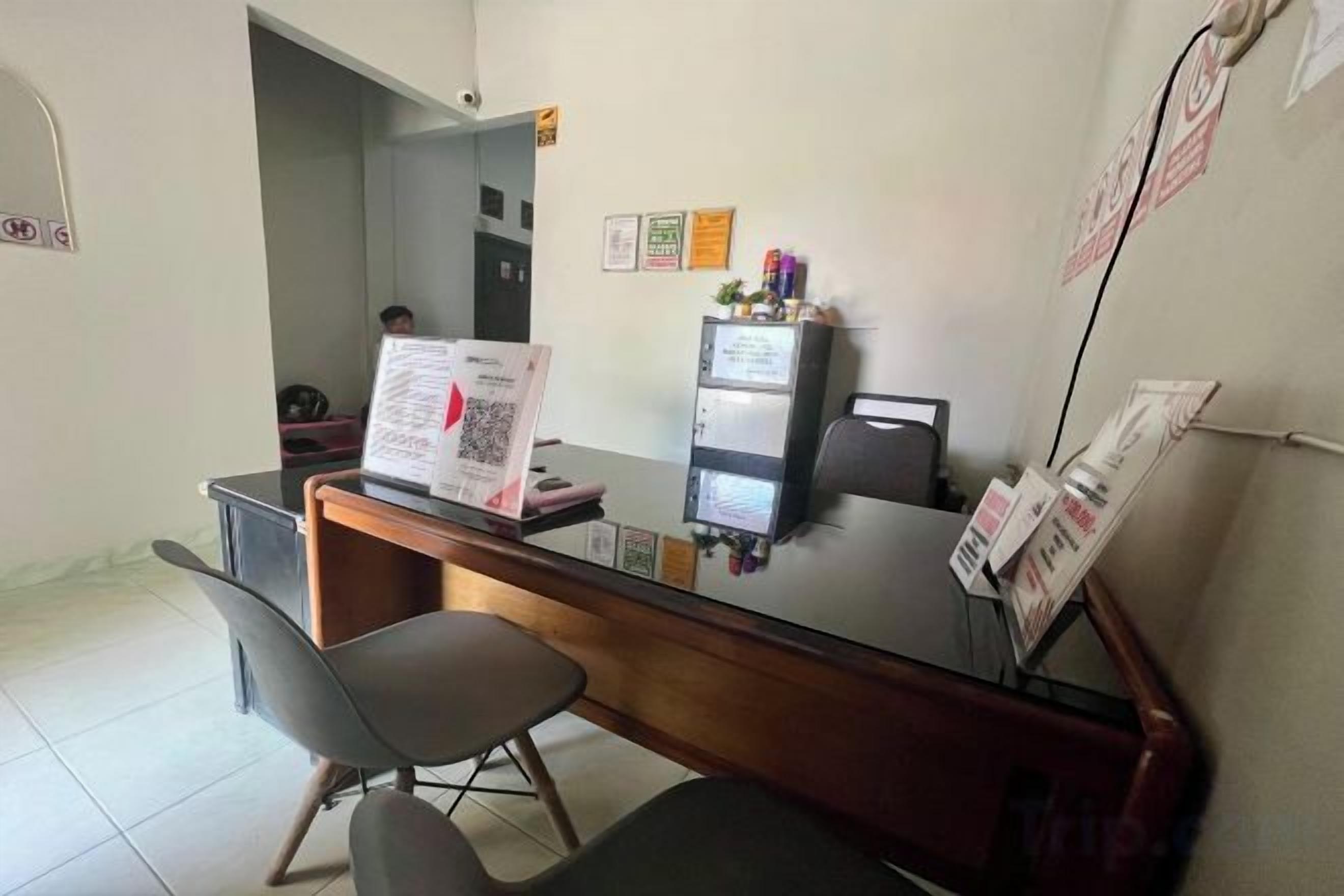 Un comptoir d’accueil équipé d’un ordinateur, d’une chaise et d’un présentoir affichant le menu.