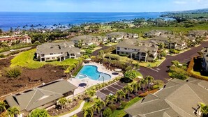 Quartiere residenziale con piscina, circondato da case, vista aperta sull'oceano e strada che conduce alla spiaggia.