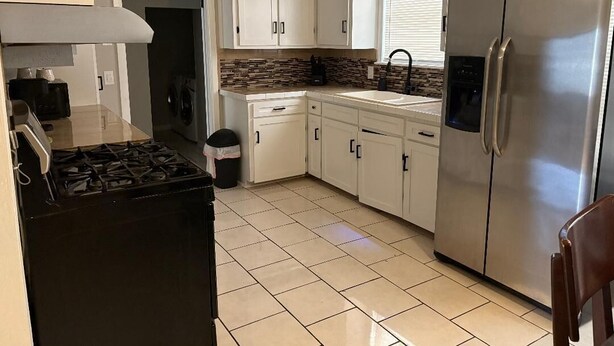 A kitchen with white cabinets, a stainless steel refrigerator, a gas stove, and a window with blinds. - Beautiful remodelded 4/1.5 bathroom home in SOUTH CORPUS CHRISTI, close to beach (Corpus Christi)