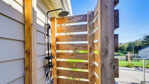 Eine Pergola aus Holz mit an der Wand befestigtem Duschkopf.