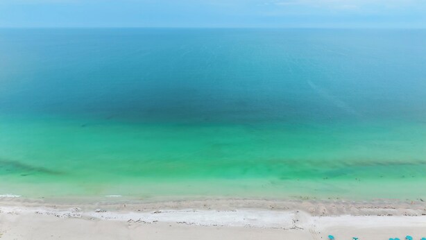 Ein Strand mit klarem türkisblauem Wasser und einem sandigen Ufer.