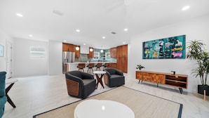 Eine moderne Küche mit Holzschränken, einem Edelstahlkühlschrank und einem Essbereich mit rundem Tisch und vier Stühlen.