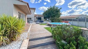 A backyard with a wooden deck, a swimming pool, and a patio area with outdoor furniture. - Cozy home in Serviers-et-Labaume (Serviers-et-Labaume)