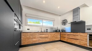 A modern kitchen with wooden cabinets, a black countertop, and a window with a view of greenery. - Cozy home in Serviers-et-Labaume (Serviers-et-Labaume)