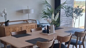 Een moderne eethoek met een houten tafel en stoelen, een potplant en uitzicht op de omgeving.