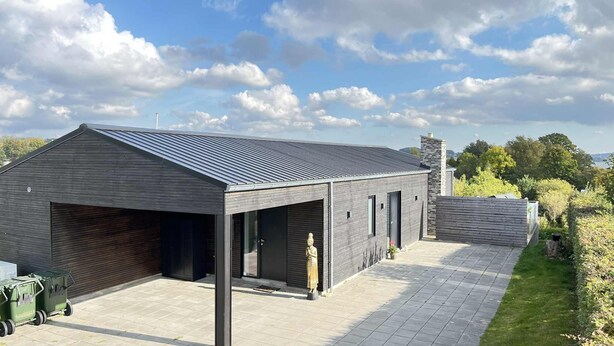 Een modern gebouw met een garage, een overdekt buitengebied en een stenen schoorsteen.