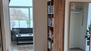 Een moderne woonkamer met een bank, een houten boekenkast en een grote spiegel.