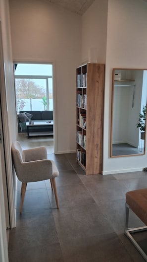 Un salon moderne avec un canapé, une bibliothèque en bois et un grand miroir.