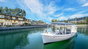 A boat docked at a marina with a row of buildings in the background.
