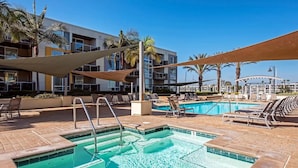 A pool area with lounge chairs and a building in the background.