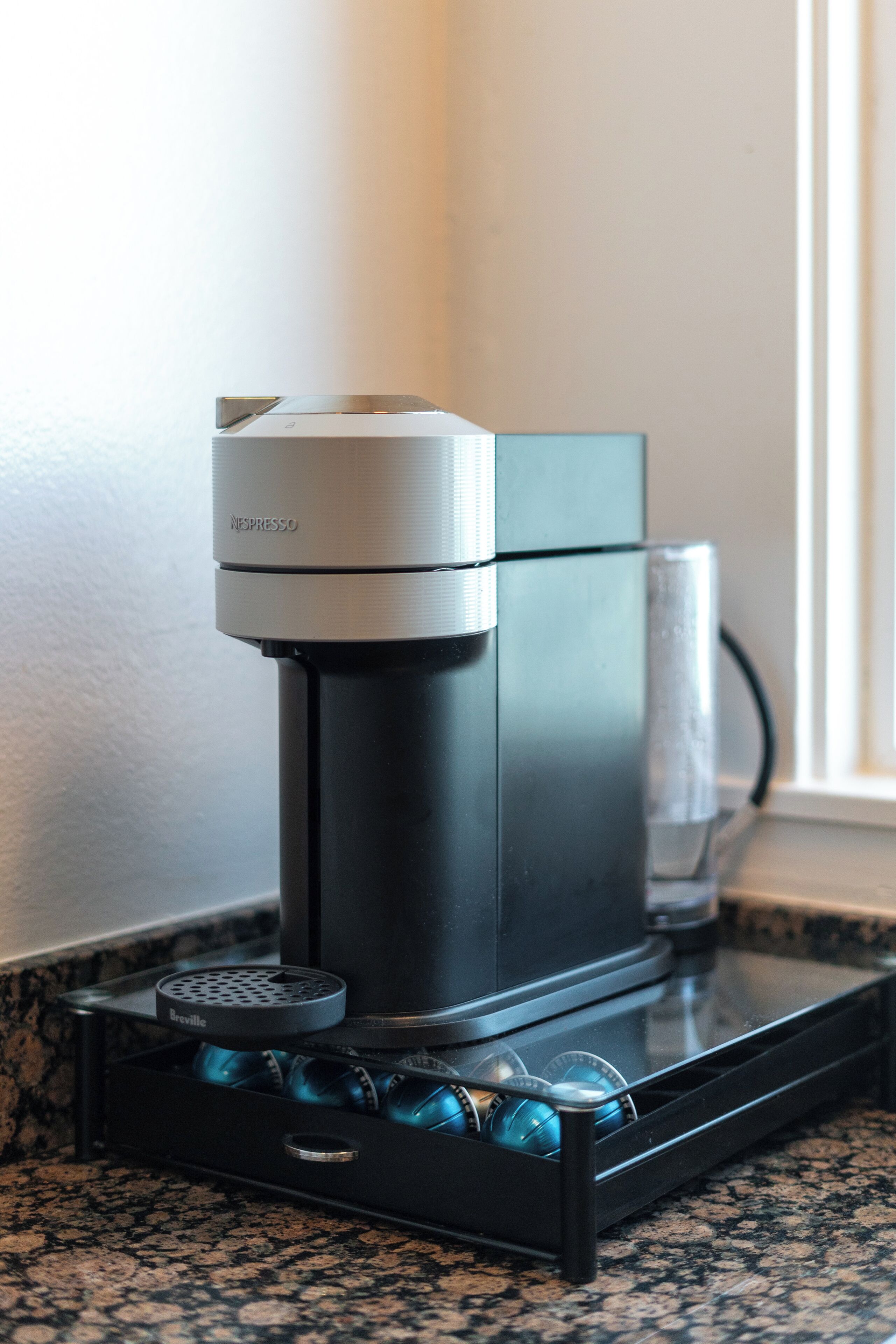 Eine Kaffeemaschine mit einem Breville-Kapselbehälter auf einer Granit Arbeitsplatte.