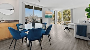 A modern kitchen with a dining area, large windows, and a ceiling fan.