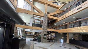 Eine großzügige Lobby mit einer zentralen Steinsäule, mehreren Ebenen mit Holzgeländern und einem Empfangstisch.
