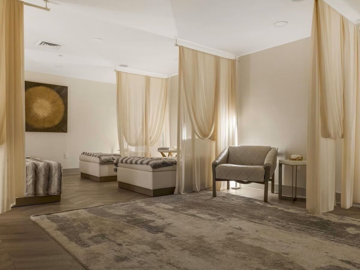 Un salón espacioso con un sofá grande, otro sofá más pequeño y una silla. Hay una mesita baja y una alfombra en el suelo.