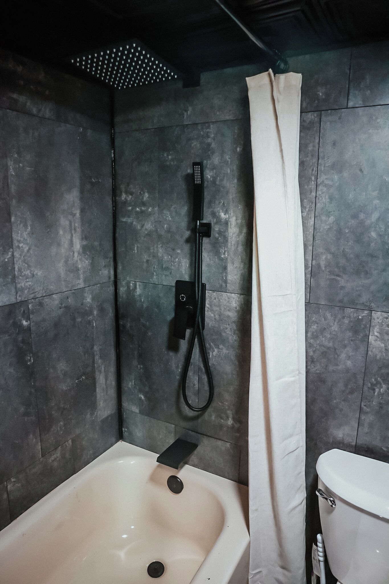 A bathroom with a bathtub, toilet, and shower curtain.