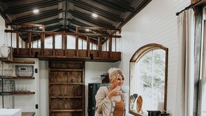 A cozy kitchen with wooden cabinets, a black leather couch, and a large mirror. - Charming Tiny Home in Pace Near Downtown and Pensacola Beach, 2 min from Walmart (Pace)