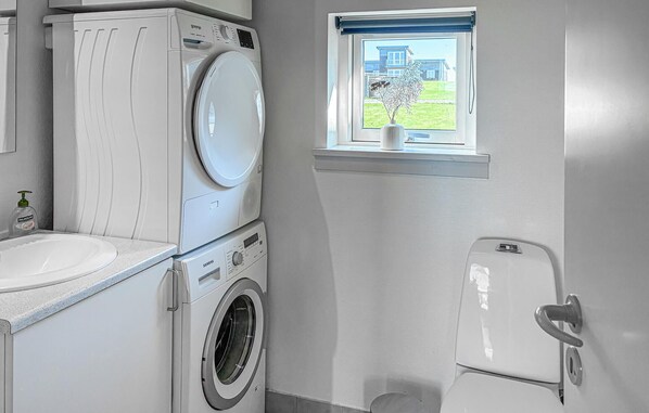 Une petite buanderie équipée d’un lave-linge, d’un sèche-linge et de toilettes.