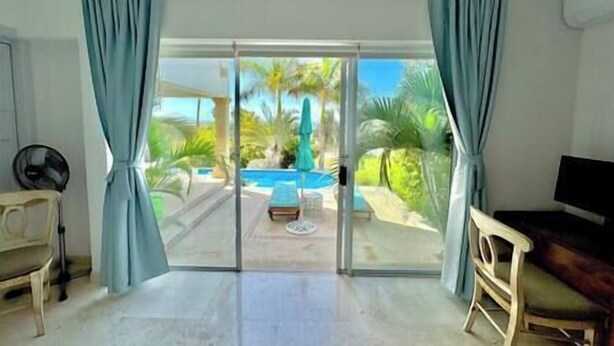 A room with a sliding glass door leading to a pool area, a chair, and a television.