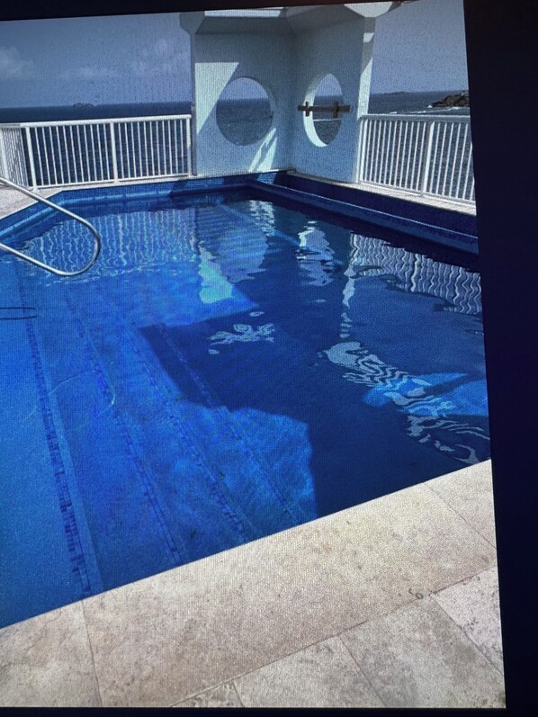 Una piscina con una scala in metallo e vista sull'oceano.