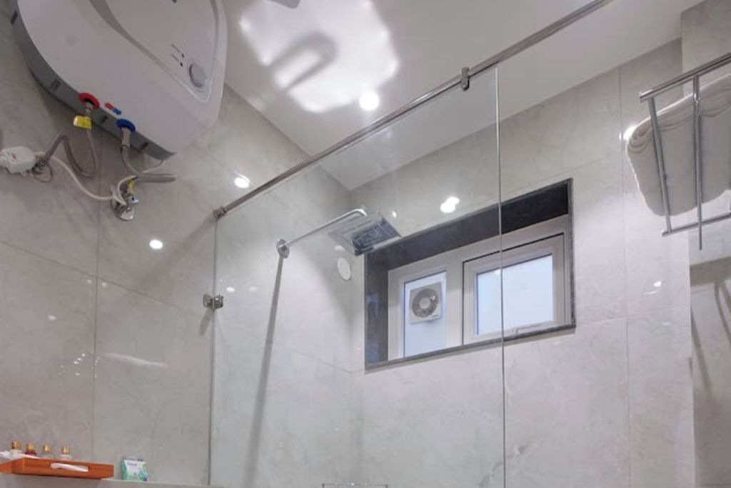 A modern bathroom with a glass shower enclosure, a small window, and a towel rack.
